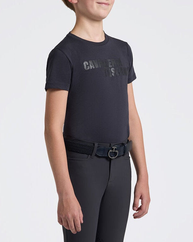 A child model wearing a dark charcoal gray short-sleeve equestrian shirt with a subtle &