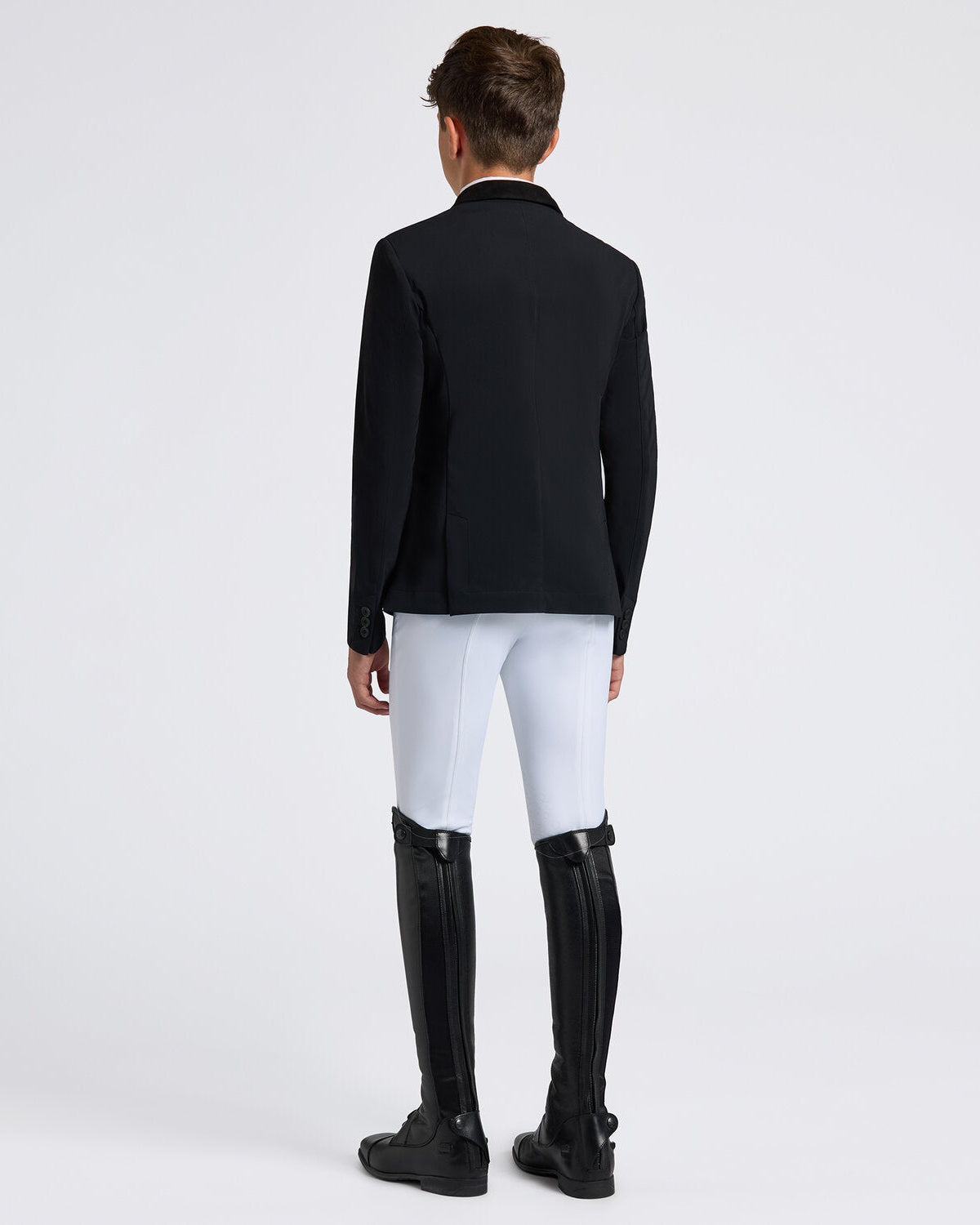 Rear view of a young rider wearing the Cavalleria Toscana CT Boys Competition Jacket With Zip, featuring a suede collar, tailored fit and buttoned cuffs.