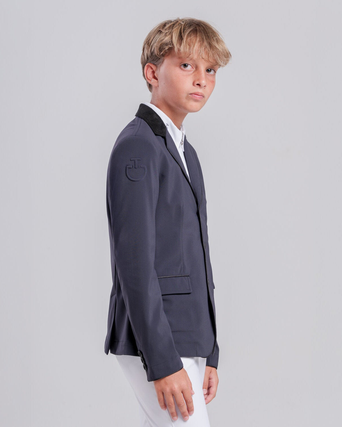 Front view of a young rider wearing the Cavalleria Toscana CT Boys Competition Jacket With Zip, featuring a suede collar, tailored fit and buttoned cuffs.
