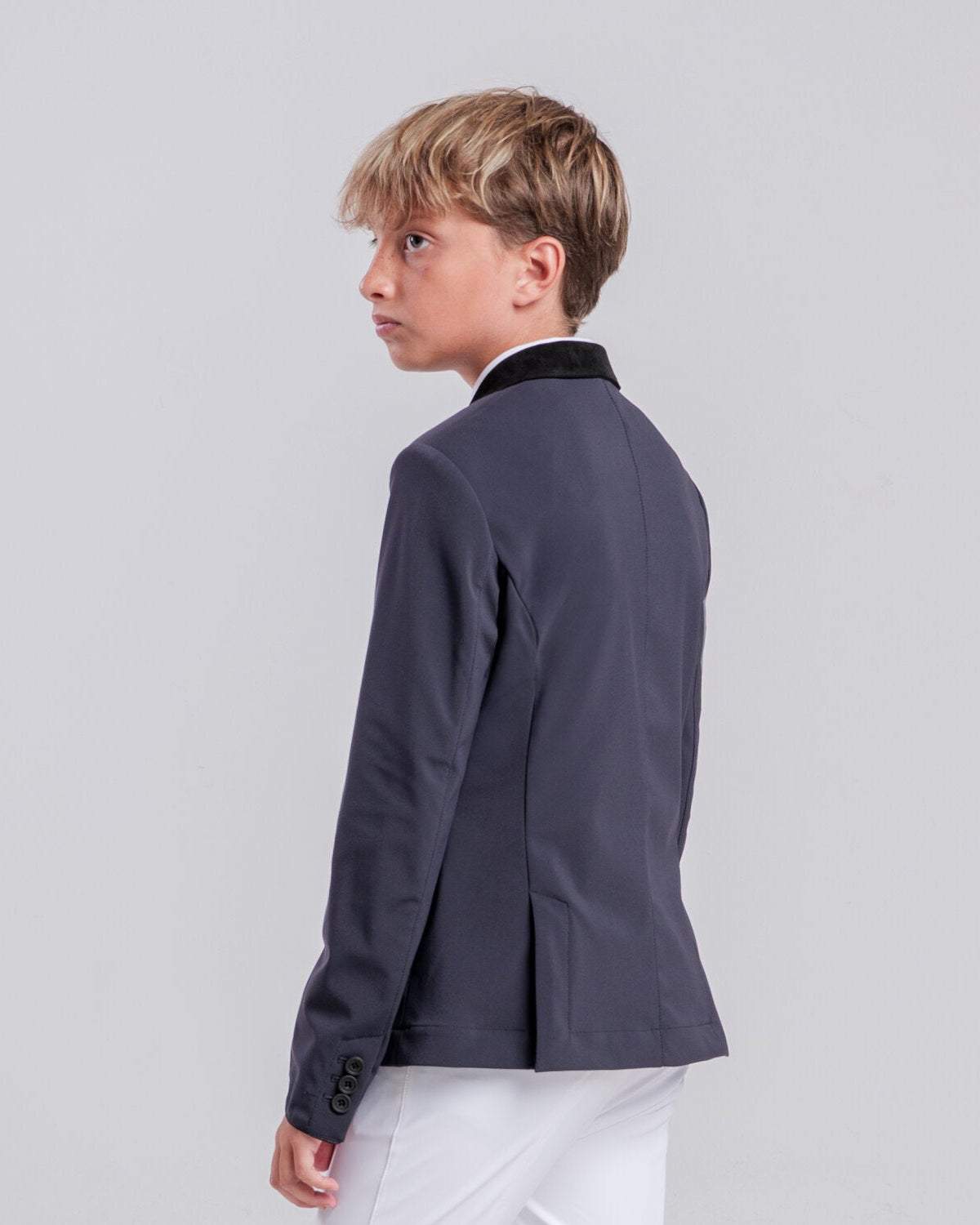 Rear view of a young rider wearing the Cavalleria Toscana CT Boys Competition Jacket With Zip, featuring a suede collar, tailored fit and buttoned cuffs.